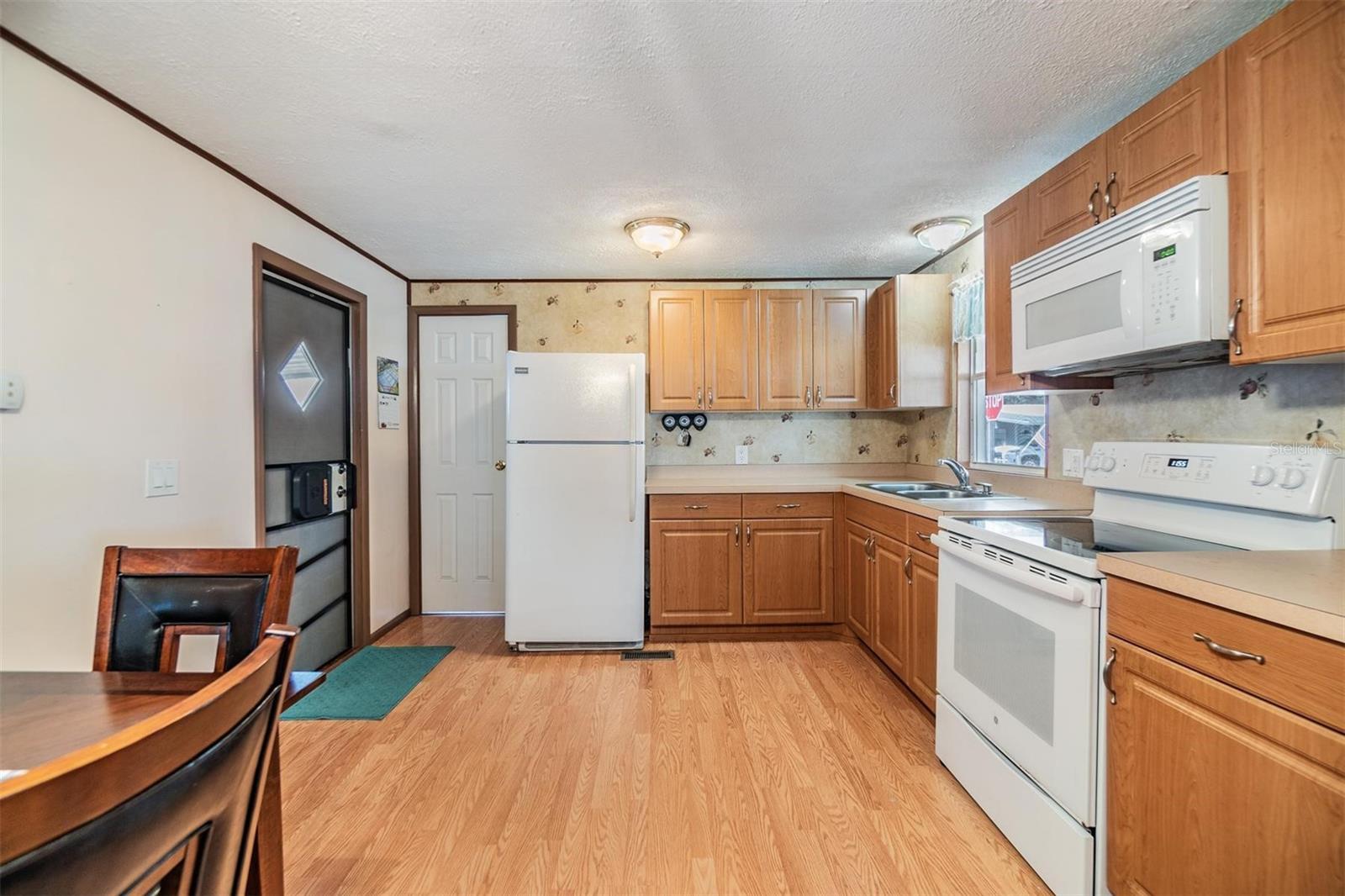 Laminate flooring, wood cabinets in this eat-in kitchen.