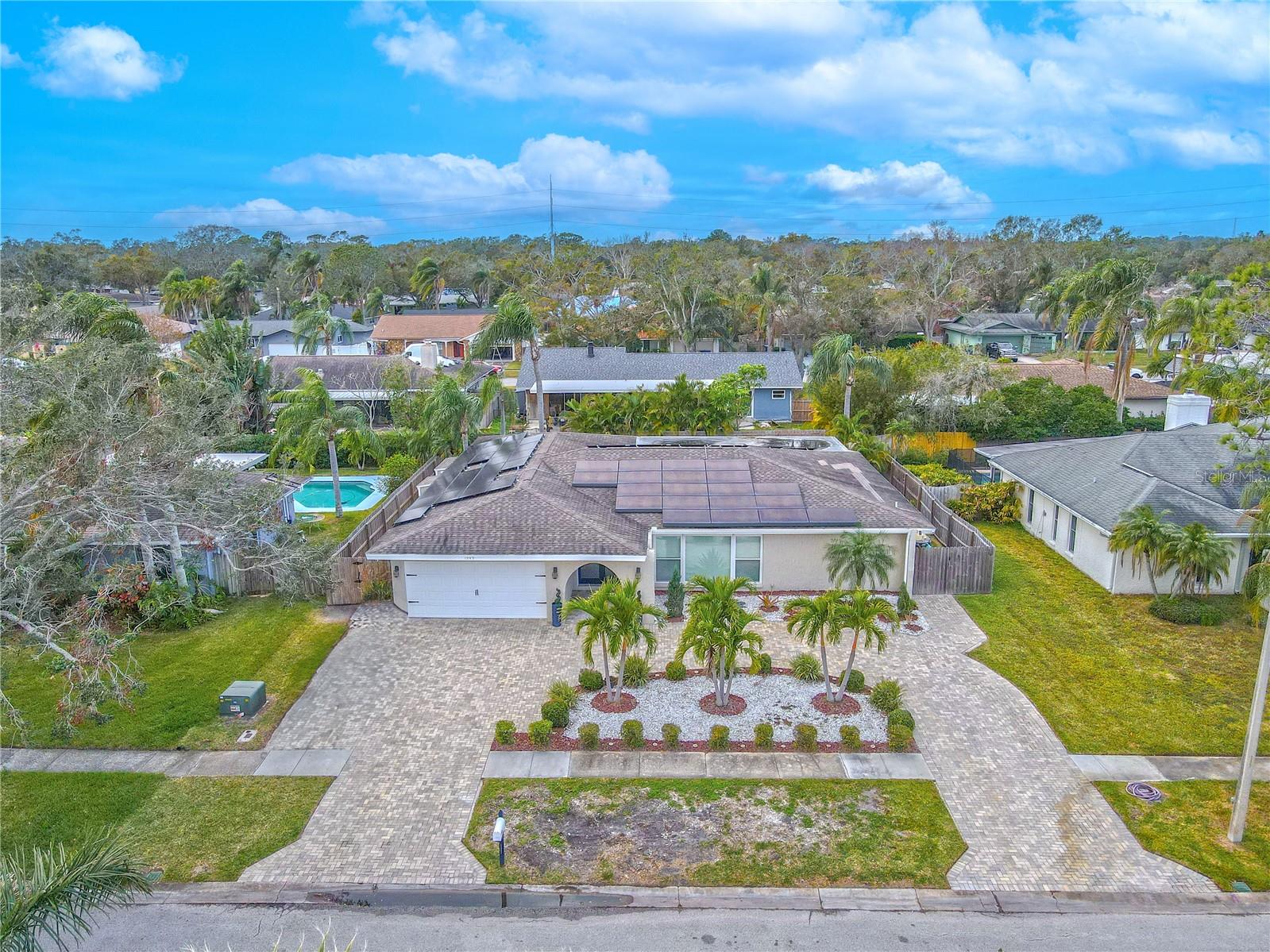 Paved circular driveway accented by tropical landscaping.