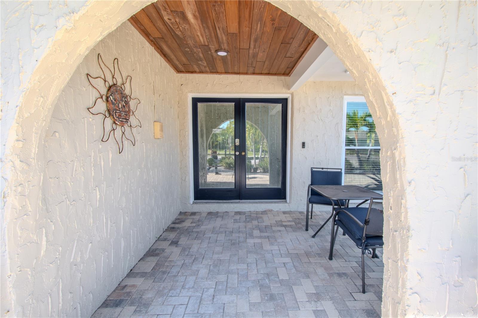 The home features an arched entryway, covered front porch with tongue and groove ceiling, pavered flooring and double glass paneled front doors for a stunning statement.