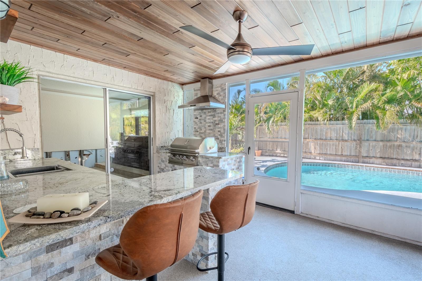 The outdoor kitchen feature a sink and bar with granite countertops.