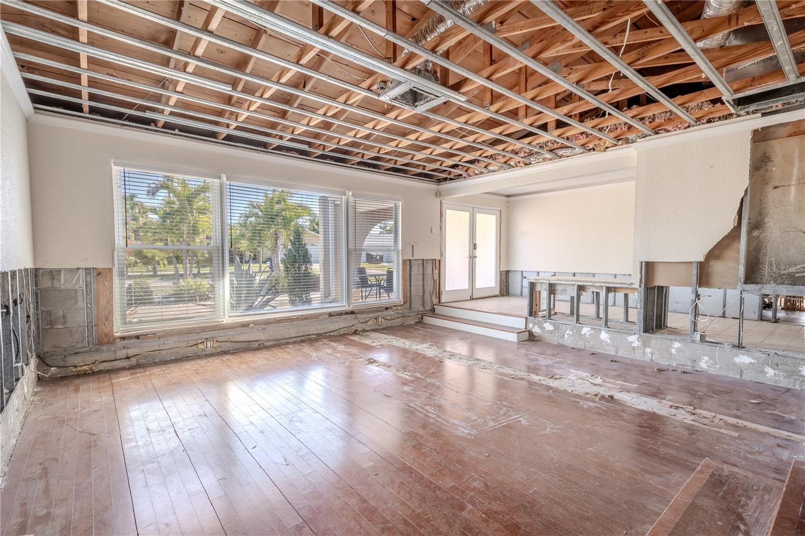 The large living room with a picture window that frames swaying palms.