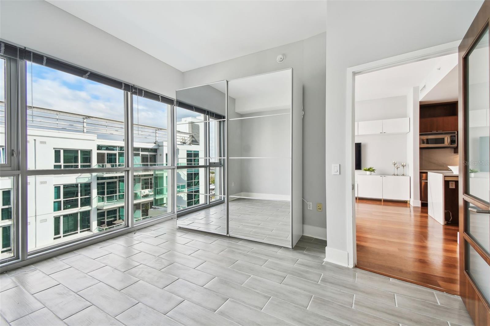 Bedroom with wall to ceiling windows allowing lots of natural light.