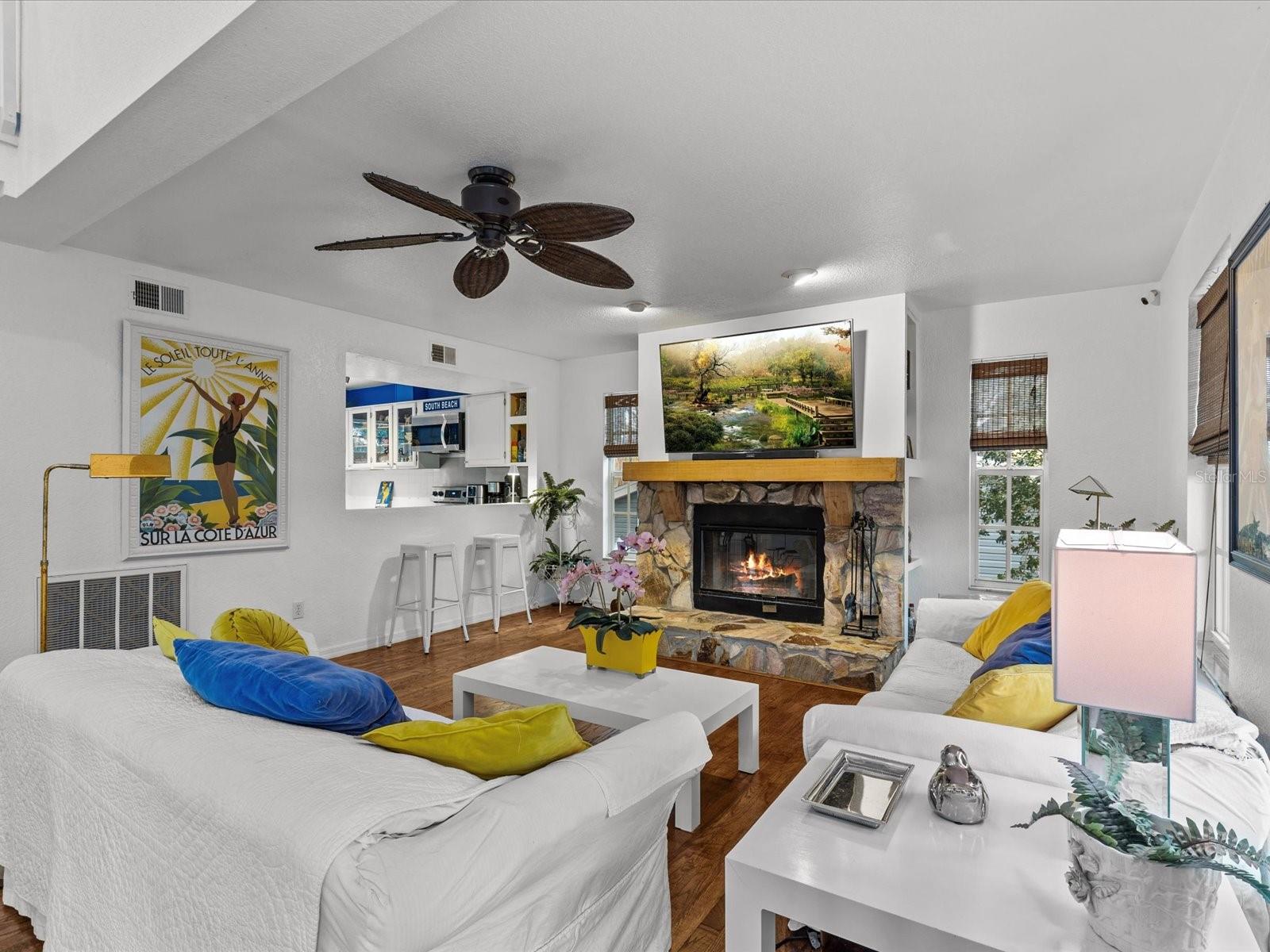 Living room off the kitchen with a wood burning fireplace and French doors out to another balcony.