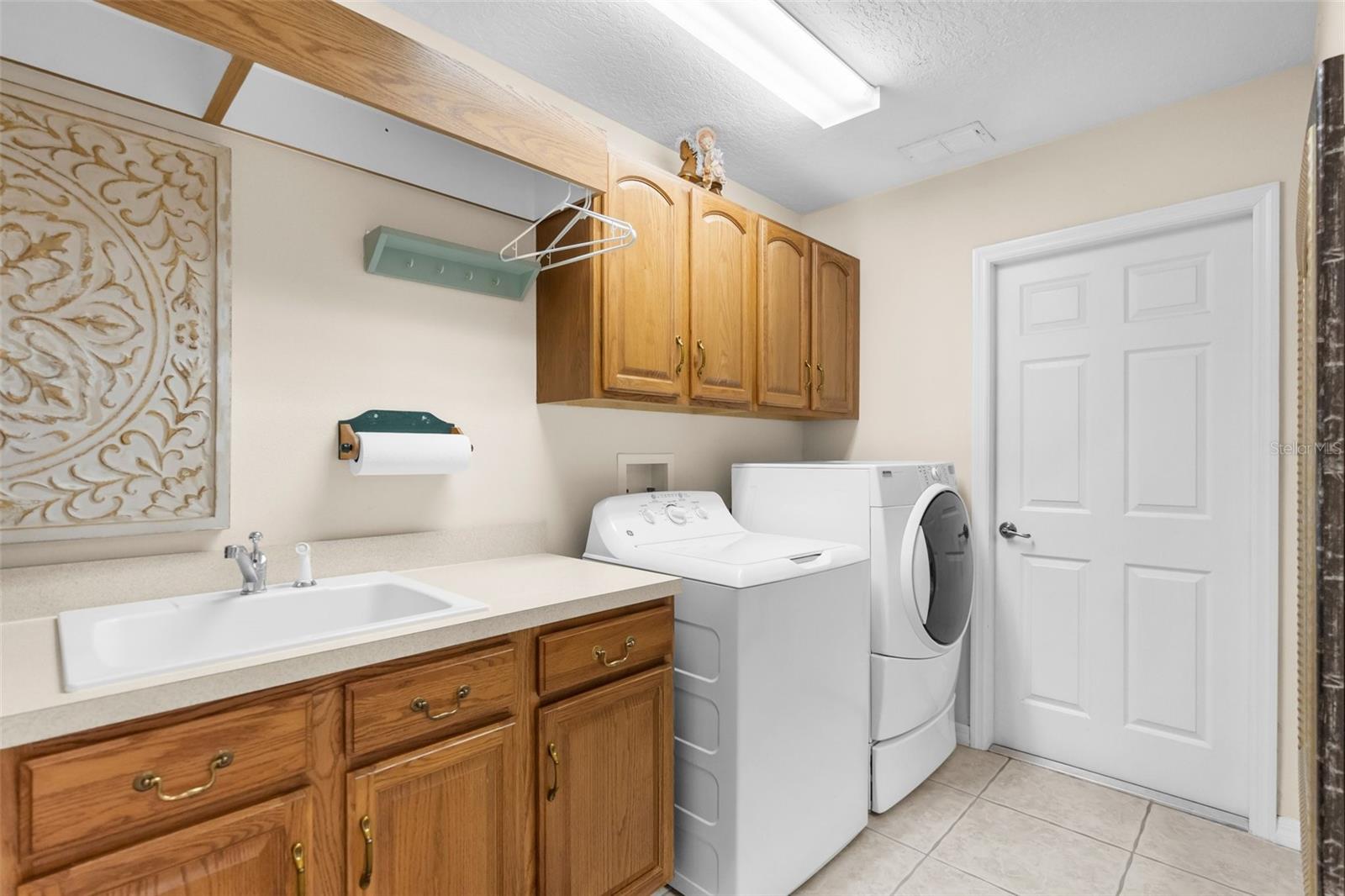 Large laundry room with extra cabinets, counter top space, and laundry sink.