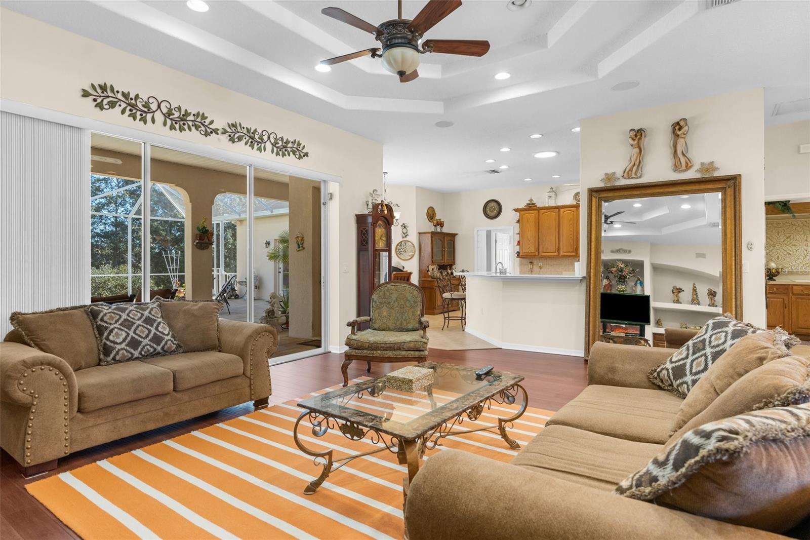 Large great room with doubel tray ceiling ans triple glass sliders overlooking the pool and lanai.