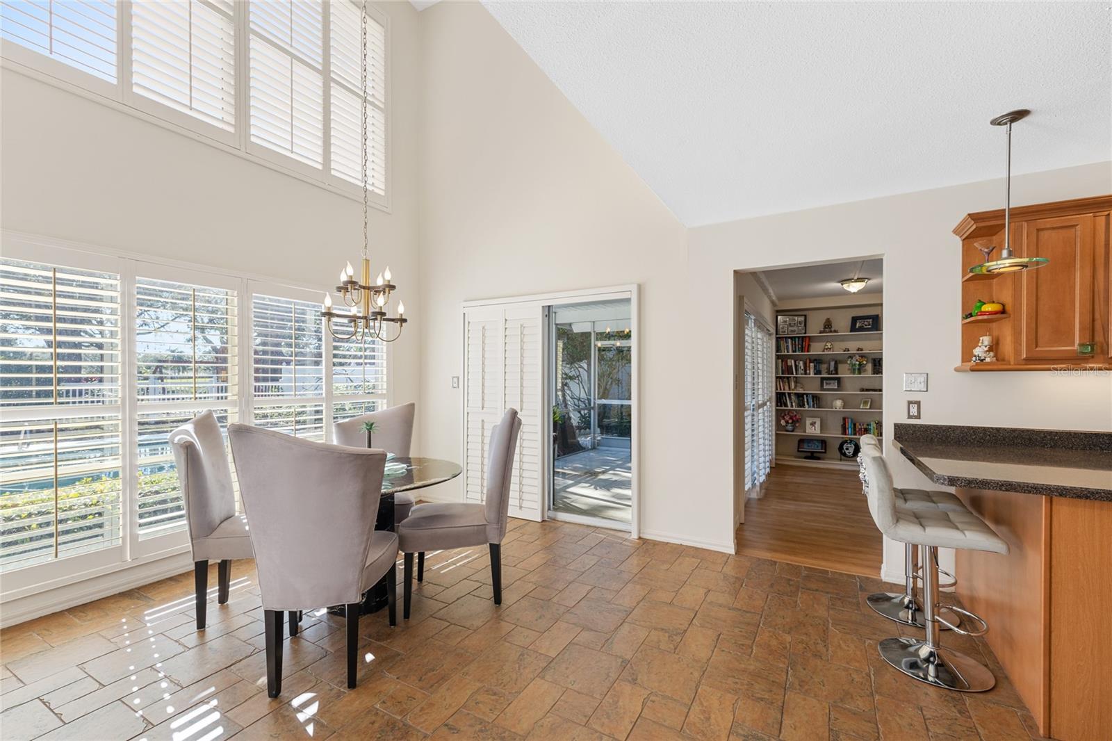 The dinette area off the kitchen boasts soaring ceilings and stunning floor-to-ceiling windows that overlook the pool. It also provides access to two separate porch/lanai areas, perfect for indoor-outdoor living.