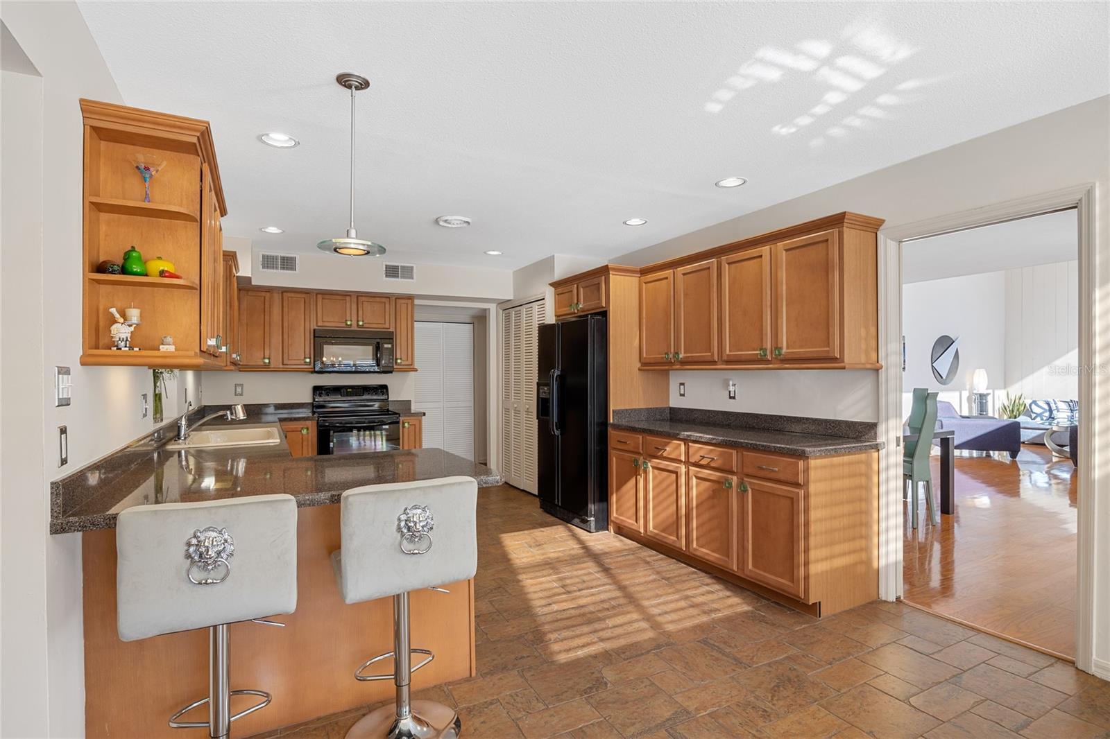 Spacious kitchen featuring tile floors, rich wood cabinets, solid surface countertops, a breakfast bar, and a convenient closet pantry