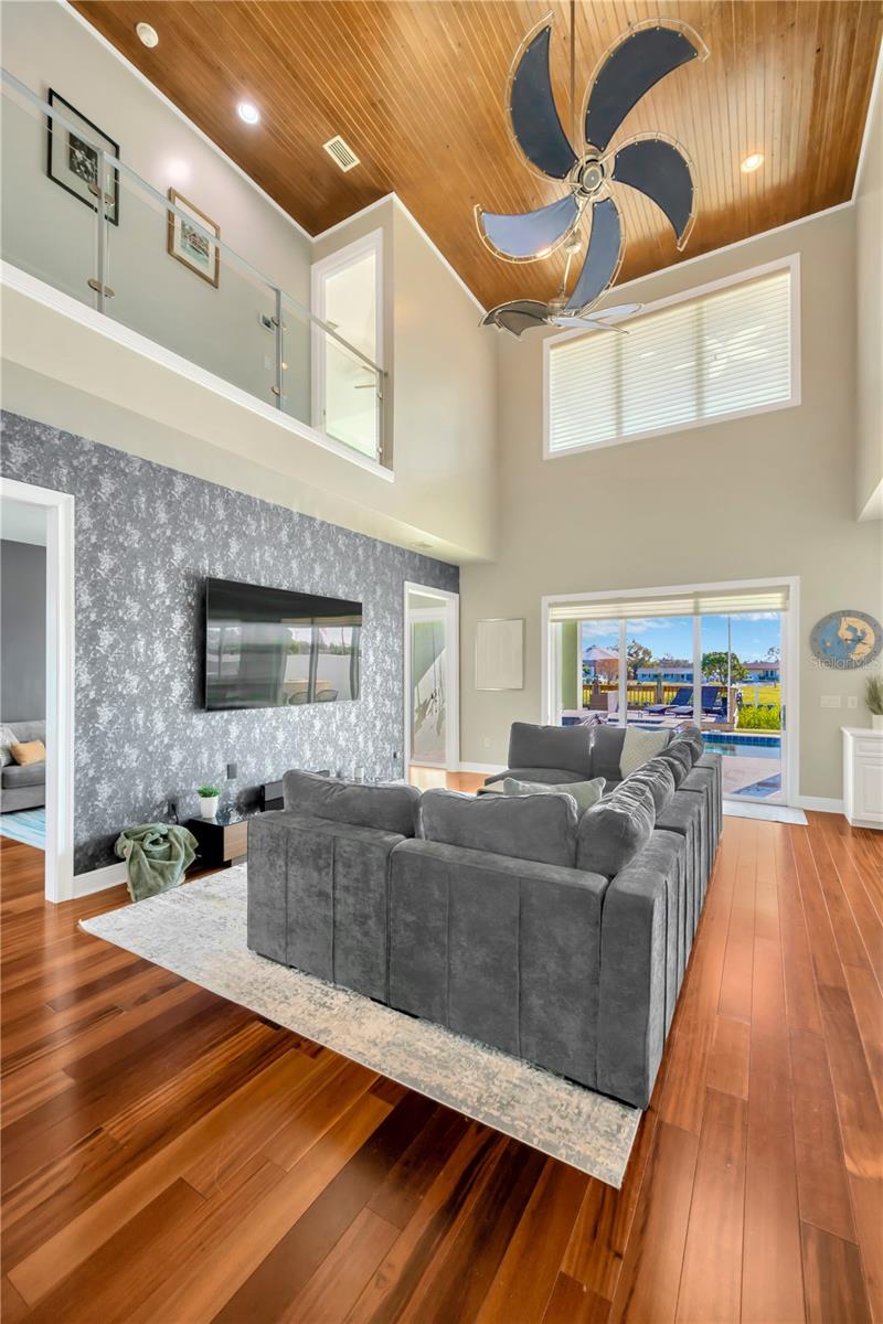 Spacious Family Room With Open Ceiling & View To 2nd Level Loft Area! Notice The Clear Glass Railing, Decorative Wood Bead Board Ceiling & Designer Ceiling Fan!