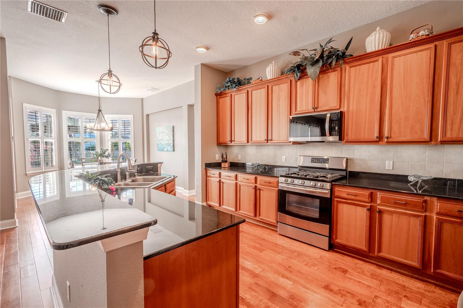 The kitchen features rich wood cabinetry, wood floors and a breakfast bar for additional seating.