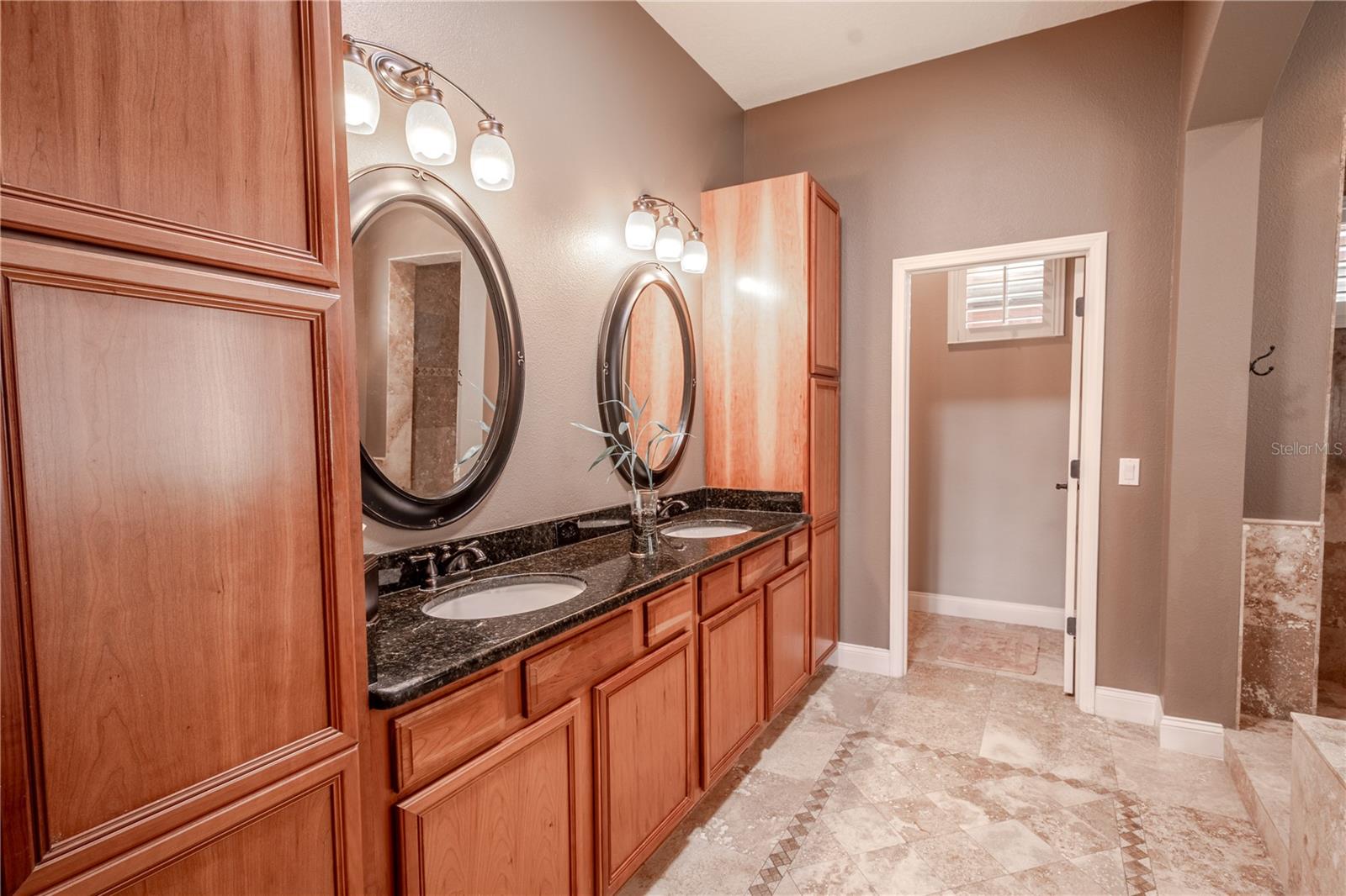 The primary ensuite bath features rich wood cabinetry, a mirrored, dual sink vanity with down light fixtures and a private water closet.