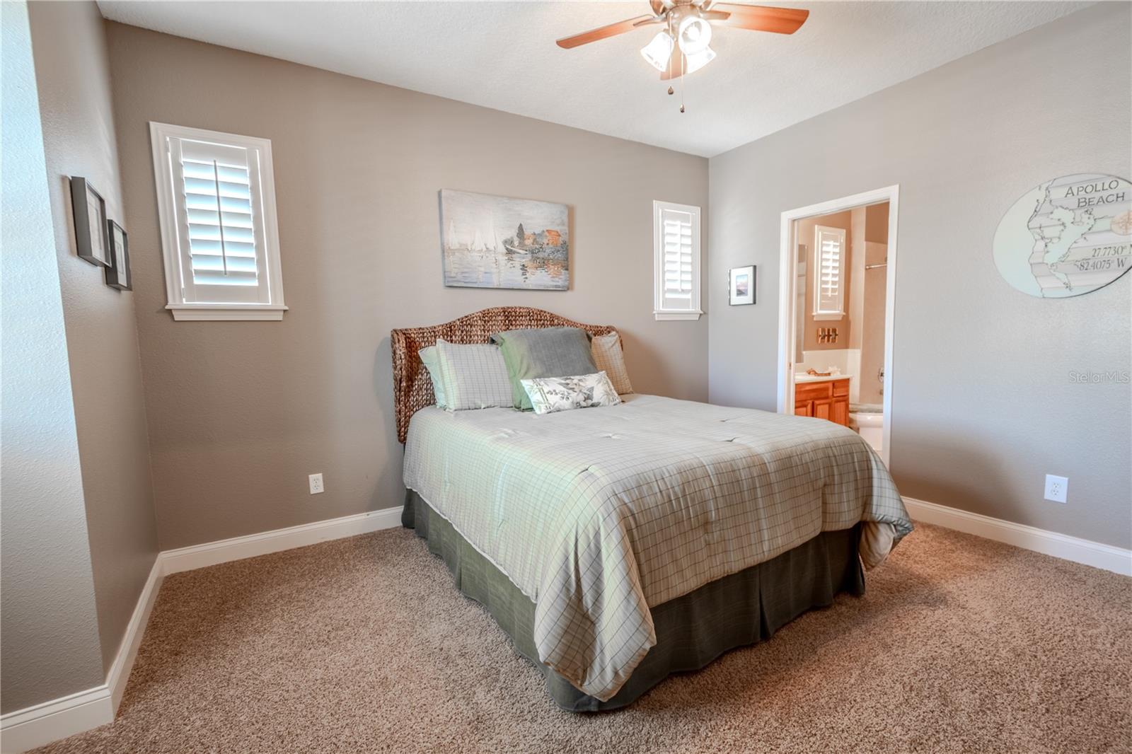 Bedroom 3 features and ensuite bath, neutral tones, a ceiling fan, plush carpet and a walk-in closet.