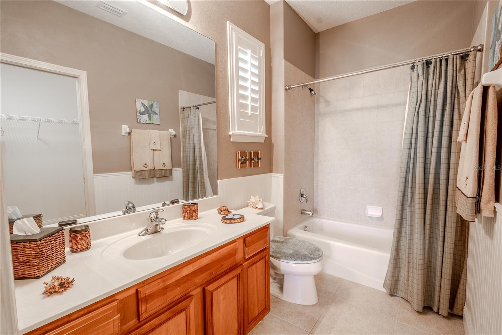 Bathroom 3, ensuite with tile floor, mirrored wood vanity and tub with shower.