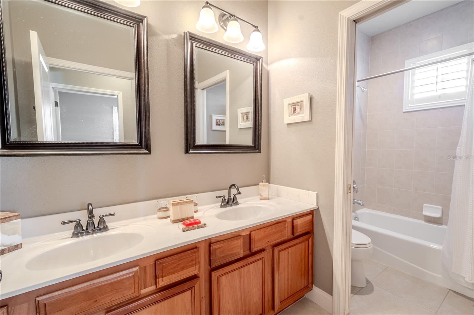 Bathroom 4 features a mirrored, dual sink vanity with down lighting and a tub with shower.