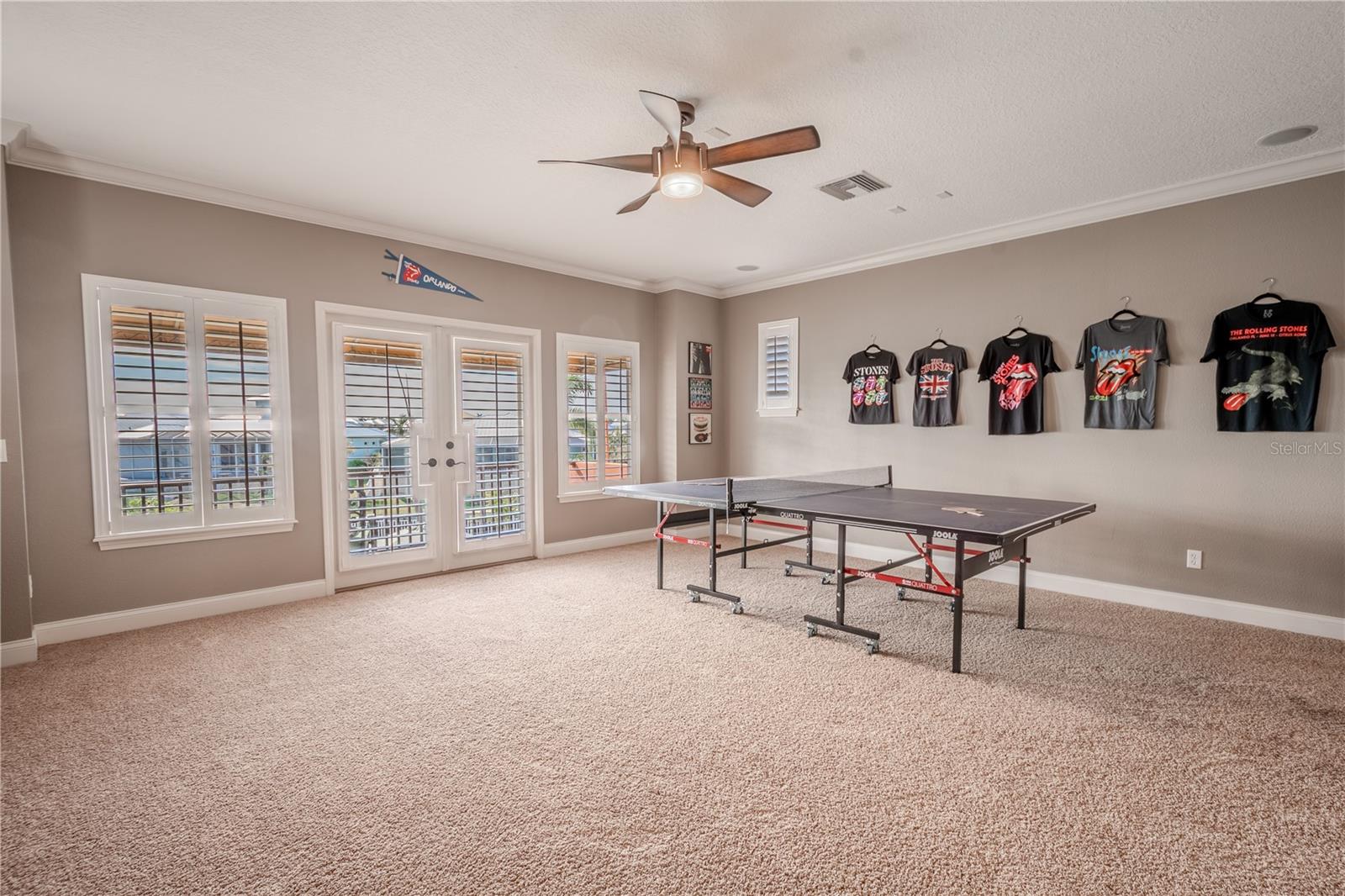 Bedroom 5 features wood shutters and french doors that lead to a private balcony with pool and water view.