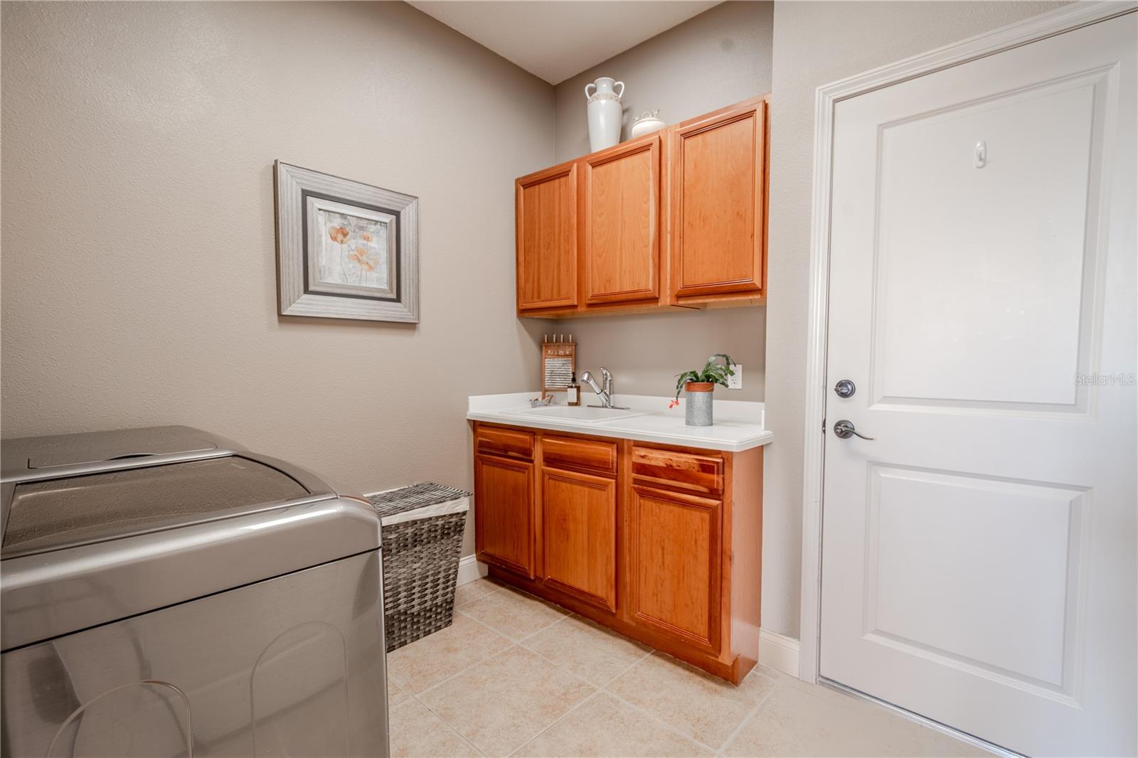 The first floor laundry room features a washer/dryer, wood cabinets and a sink.