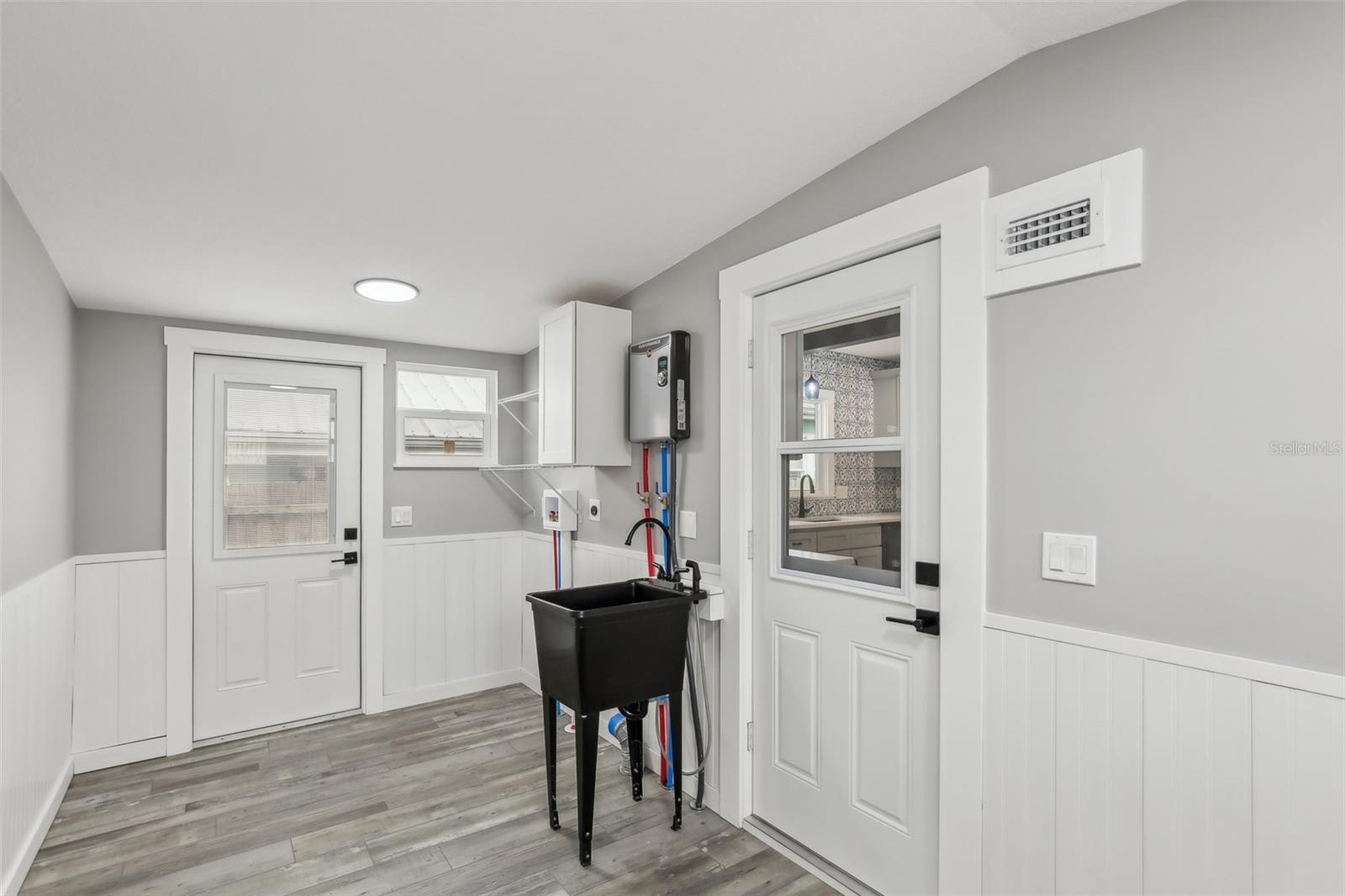 Mud Room with washer and dryer hookup, sink, storage cabinet, and your new tankless hot water heater.