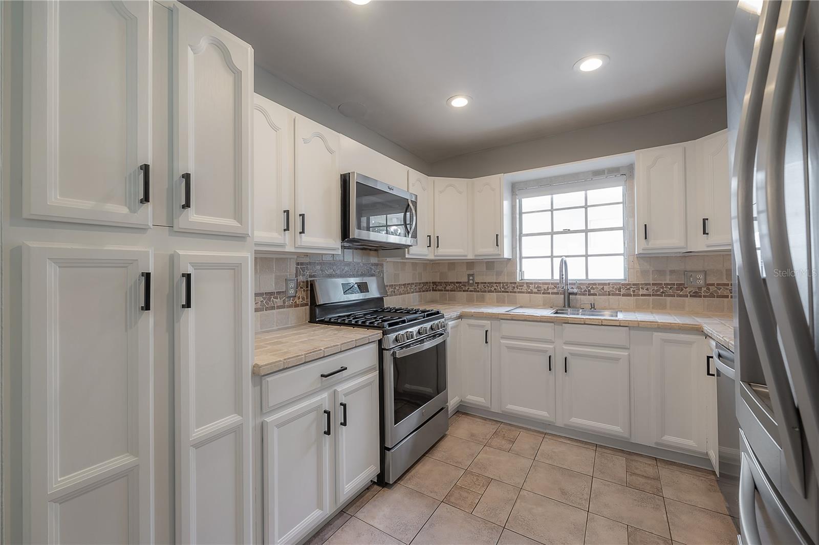 White cabinetry and a natural gas range with four burners and a griddle