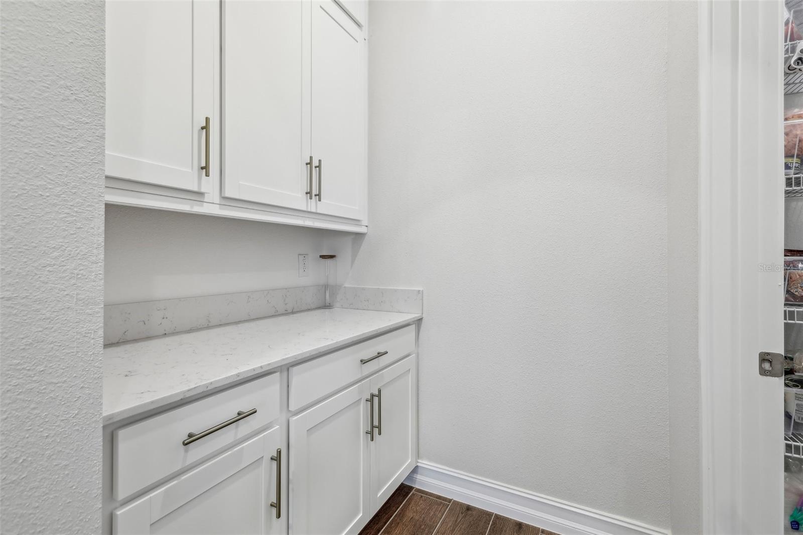 butler pantry with additional cabinets and quartz counter spaces