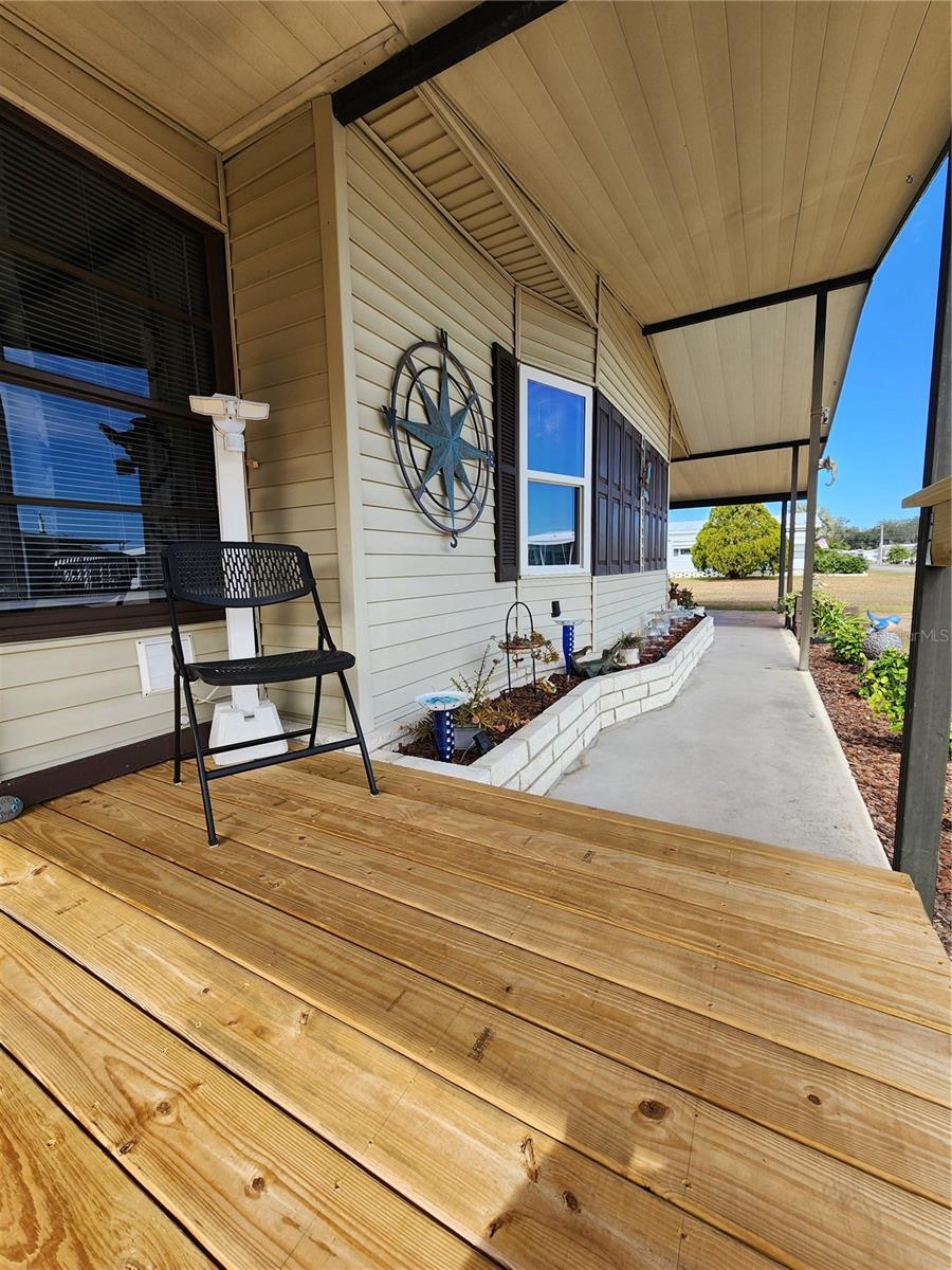 Covered front deck & wide front overhang with sidewalk & planter.