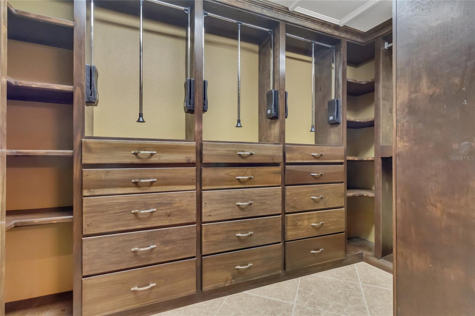 The primary bedroom closet has custom-built shelving with pull-down hanging rods