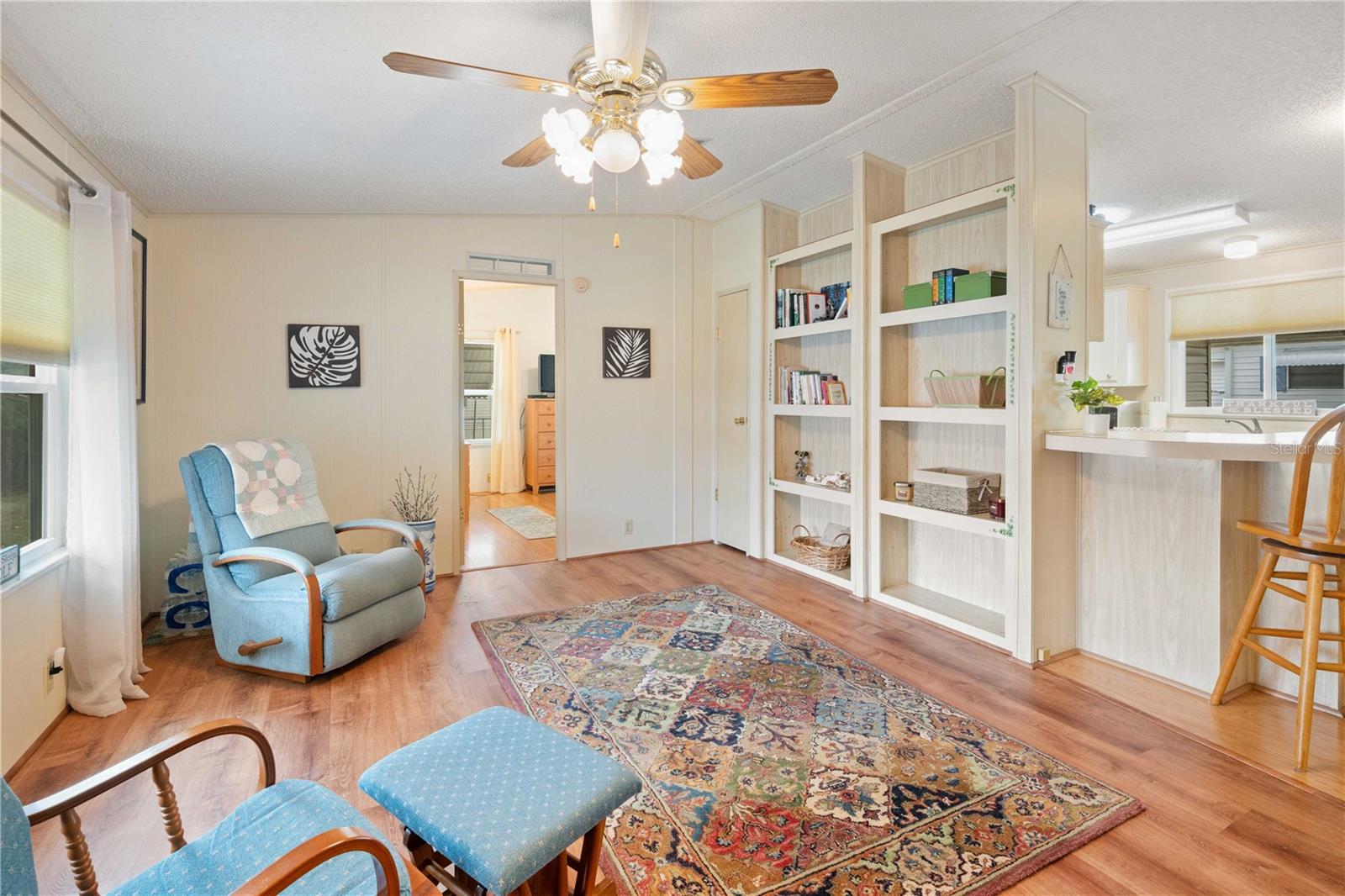 Living room has updated flooring, ceiling fan and built-in shelves.