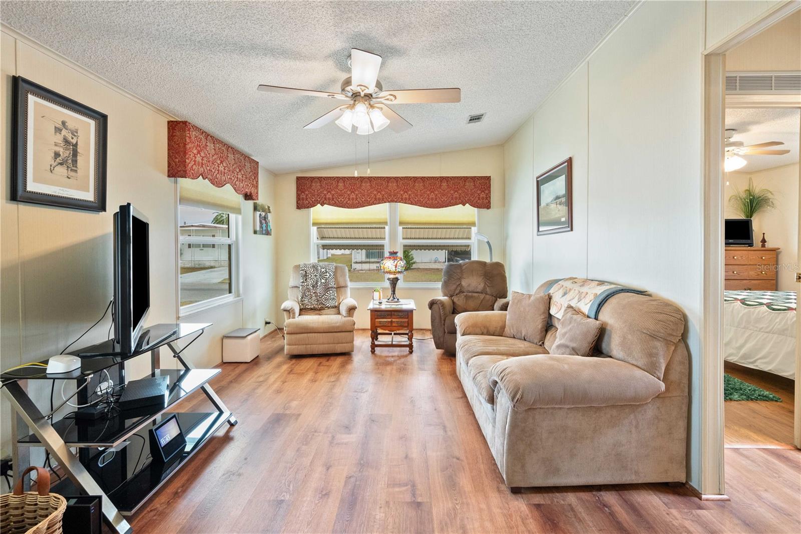 Family room has updated flooring, ceiling fan, and is fully furnished.