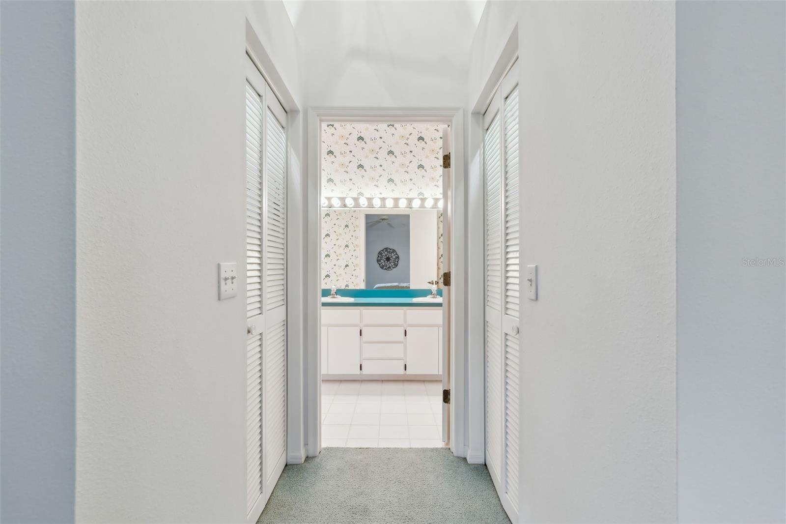 Dual walk-in closets before entering primary bathroom