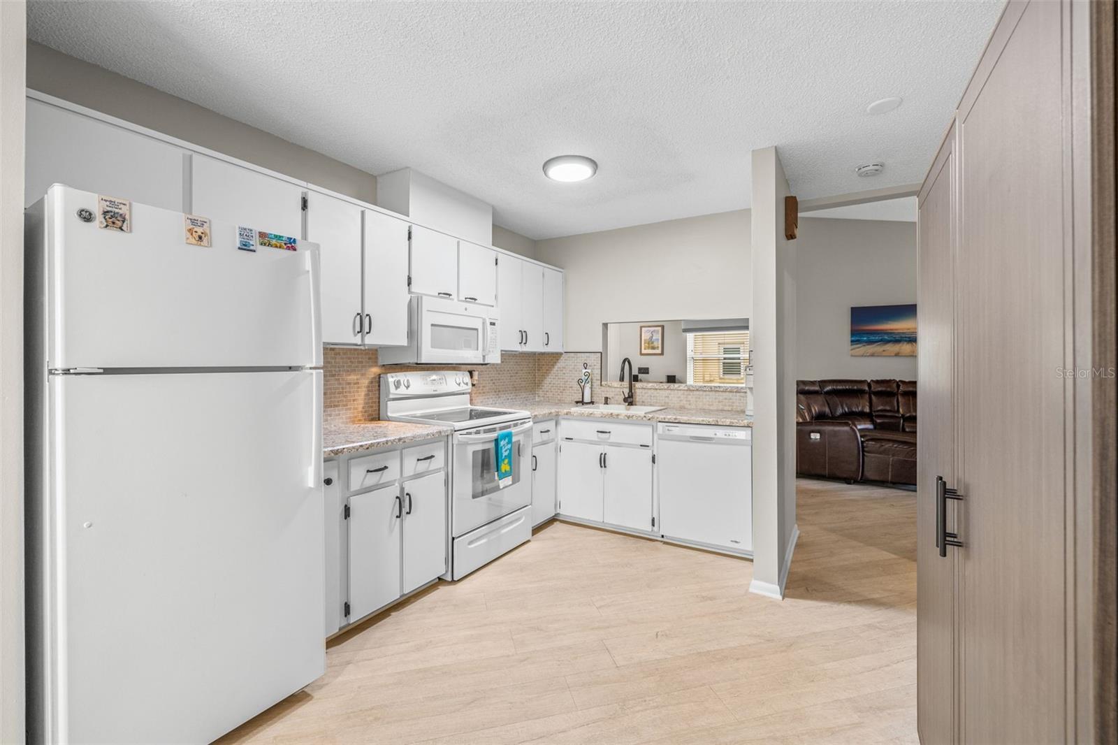 View into large kitchen from eat-in breakfast area! Nice and bright with plenty of cabinets and storage! Notice the pass-thru to the dining room for easy entertaining!