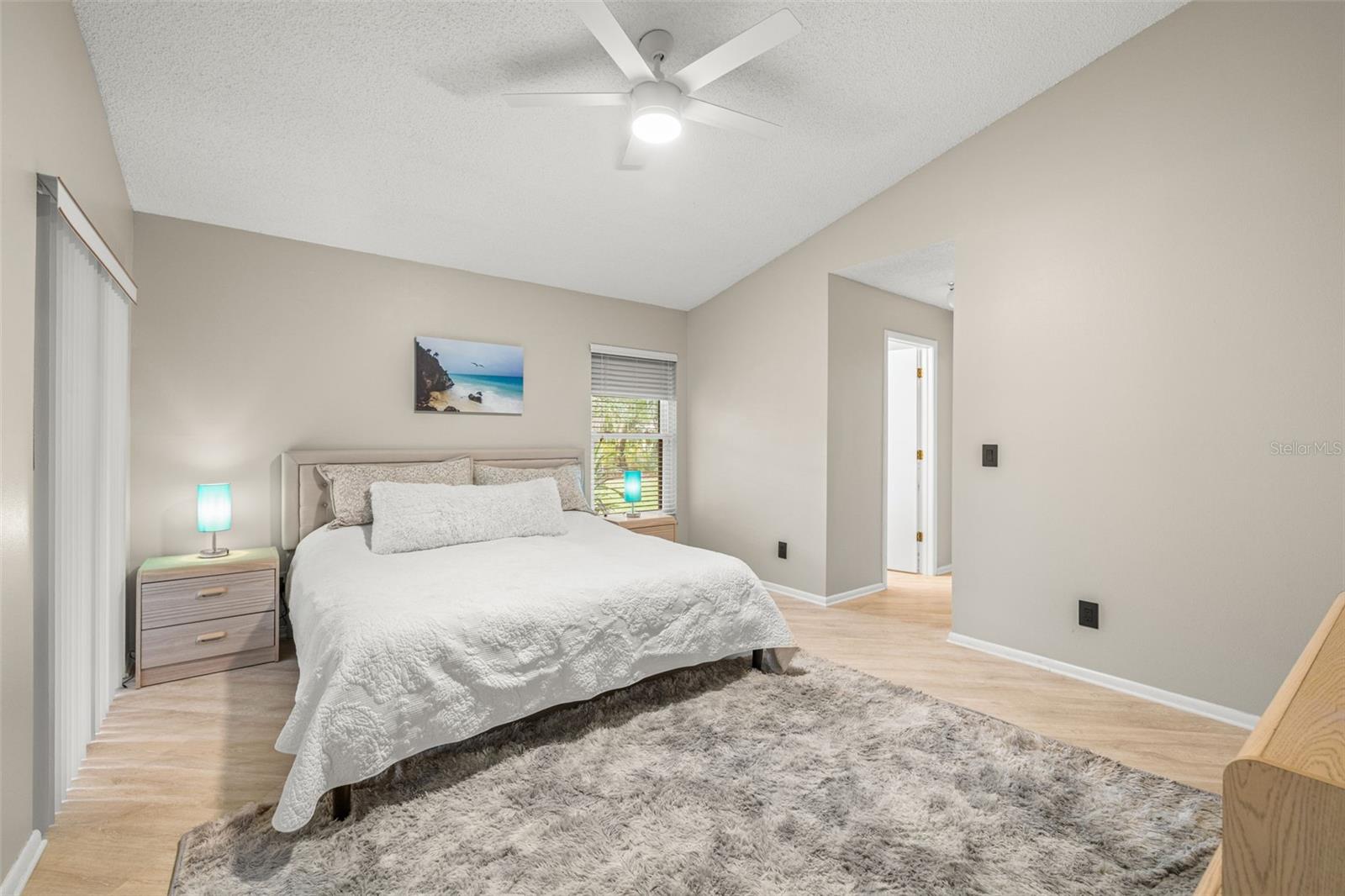 Ex-large Primary Bedroom near the main living area. High ceilings, ceiling fans, and a sliding glass door that leads to the lanai. The Primary bedroom also features a completely remodeled en-suite bathroom with walk-in shower, rain shower head, updated fixtures, large format, on-trend tile in the shower and floors.