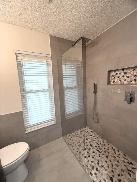 Primary bathroom just renovated with large format tile, an extra-large shampoo niche, updated fixtures, rain shower-head and pebble floor.