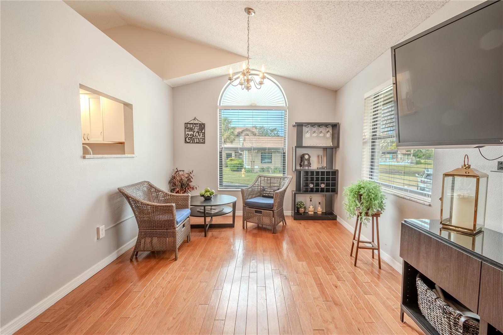 The dining room chandelier is framed by the arched floor to ceiling window. There is a convenient pass through from the kitchen.