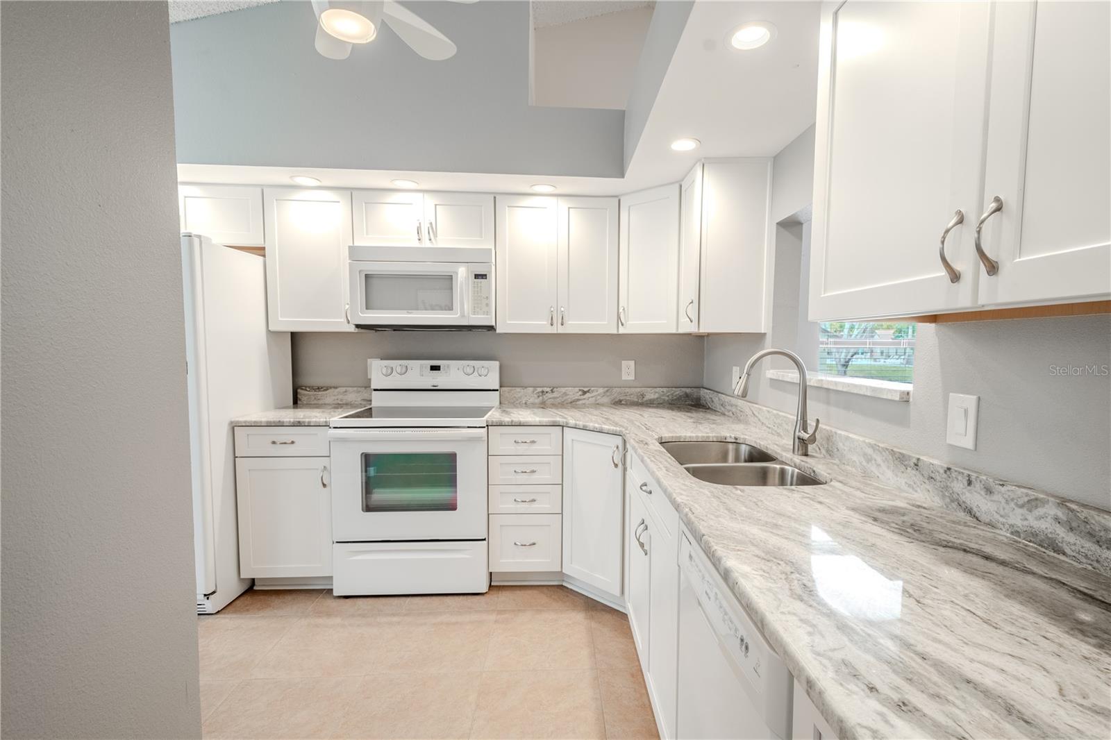 A ceramic tile floor (easy to maintain) a stanless steel double basin sink with pull-down sprayer, and a ceiling fan with light kit round out the kitchen.