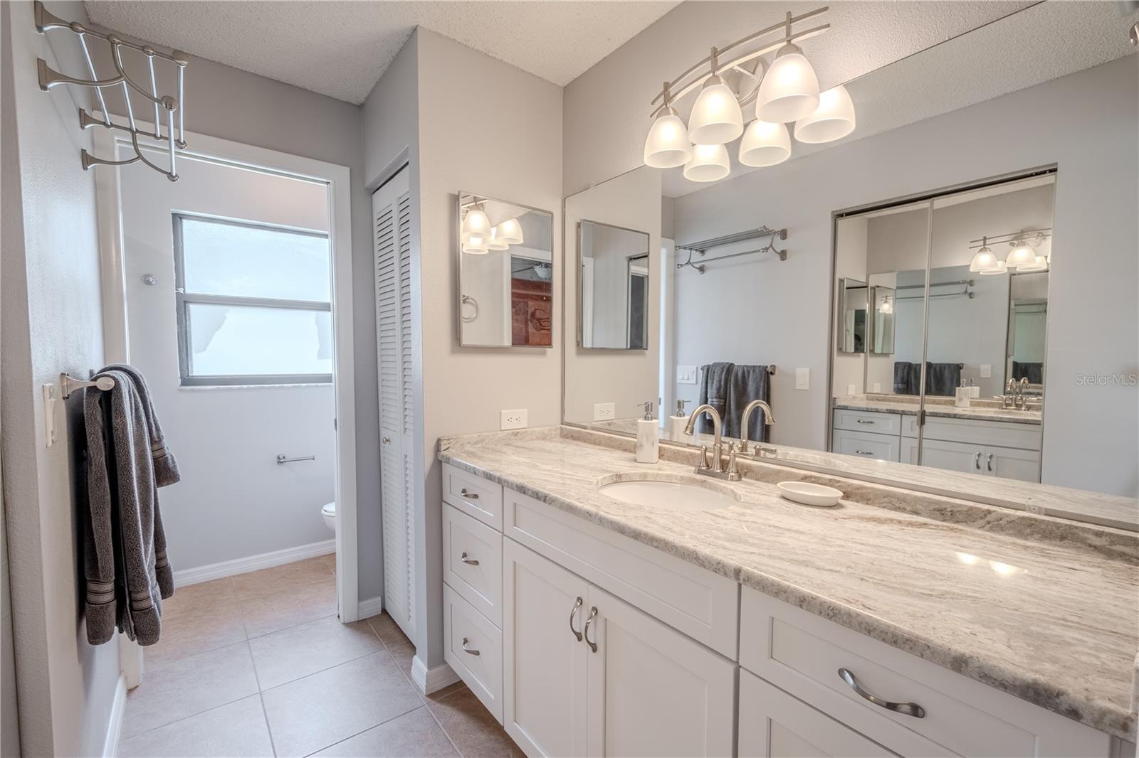 The primary ensuite bath features and upgraded mirrored vanity with down light fixture and storge, tastefyl sone counters and a linen closet.