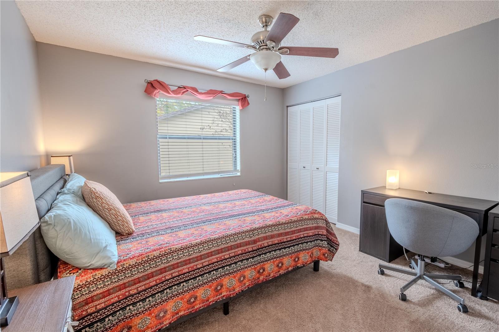 The 2nd bedroom features a built-in closet, ceiling fan with light kit, carpet and neutral tones.