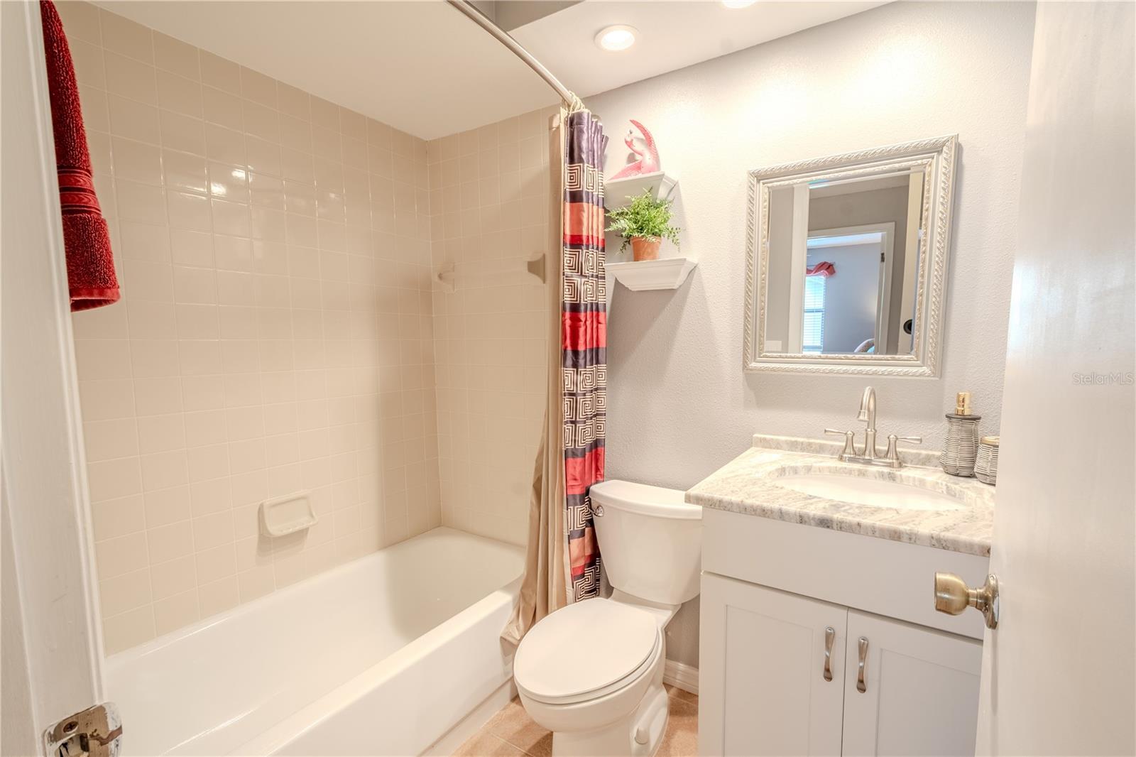 2nd bathroom features and upgraded mirrored vanity with stone counterop and storage, a tun with shower, ceramic tile floor and recessed lighting.