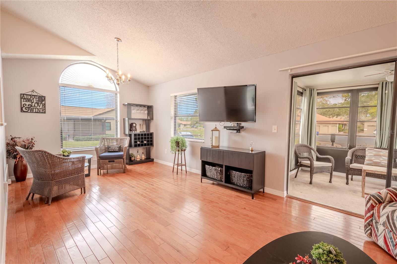 The living room is open to the dining room. The dining room has a wood floor, chandelier and beautiful arched window.