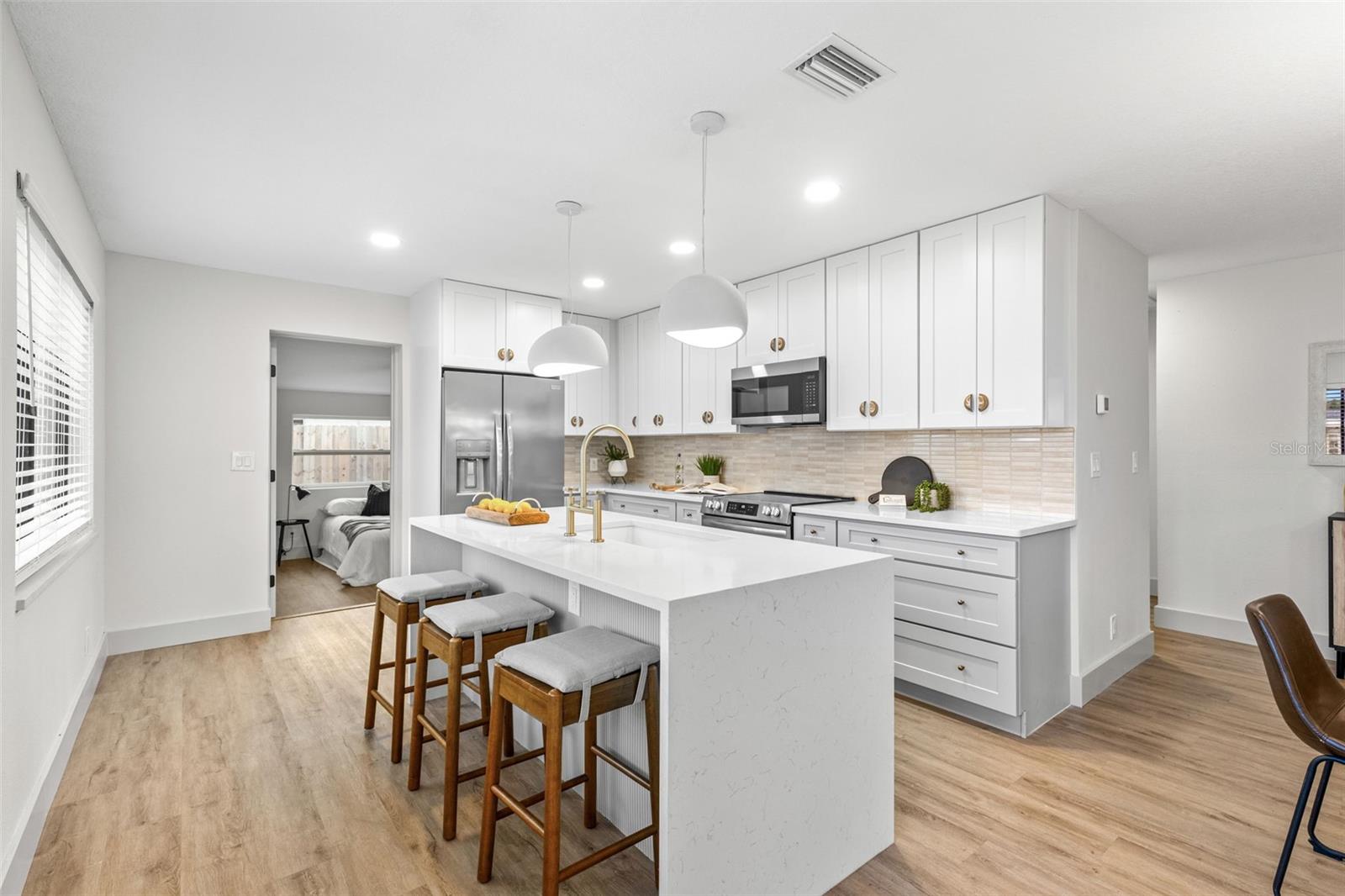 Updated kitchen with Quartz waterfall edges, stainless steel appliances, brass hardware