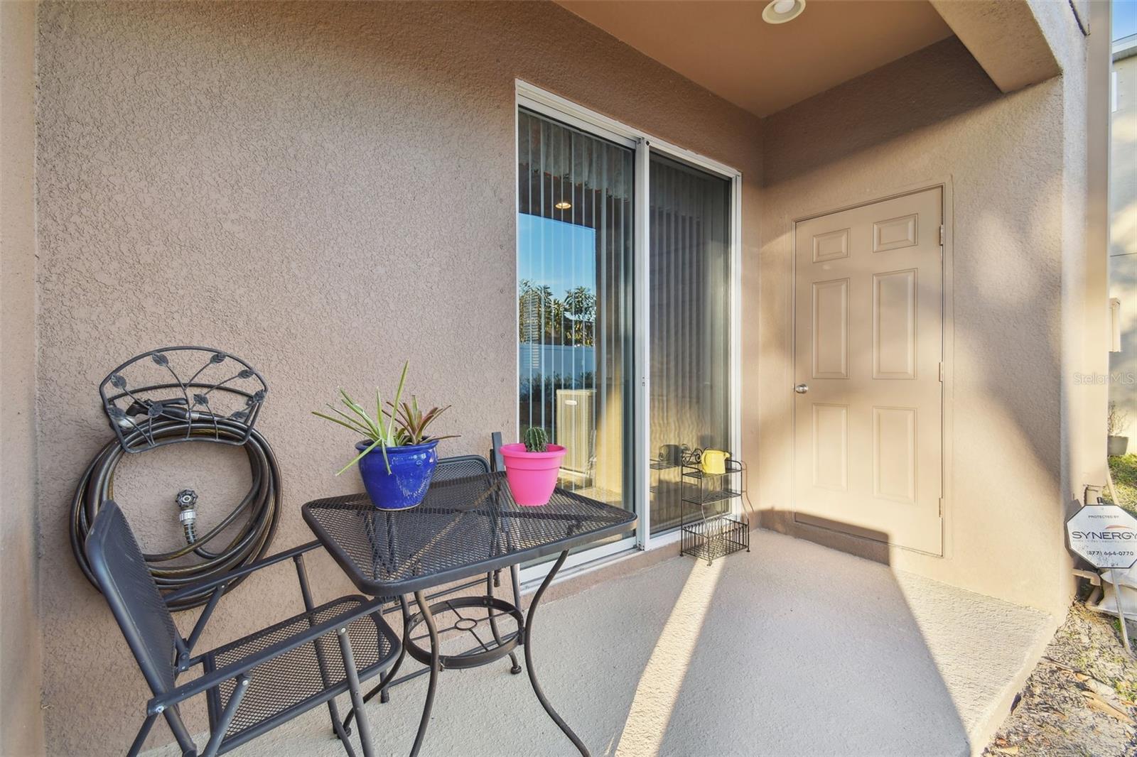 Covered lanai. Door to the right houses the water heater and electrical panel and shelving for additional storage.