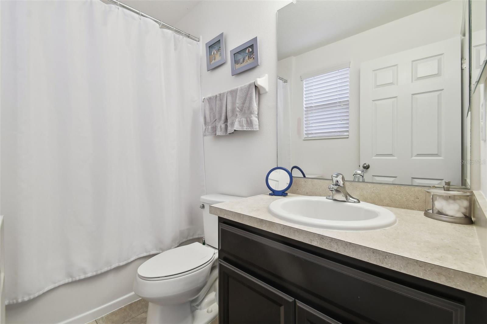 Second bedroom ensuite with single vanity and tub with shower.