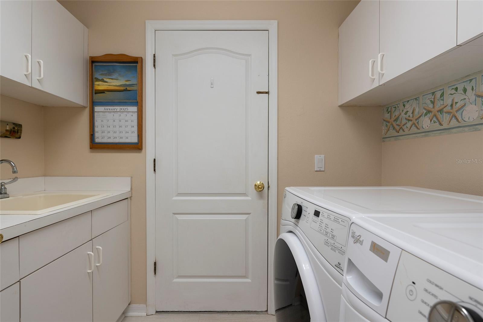 private Laundry Room with cabinets and sink leads from kitchen to garage