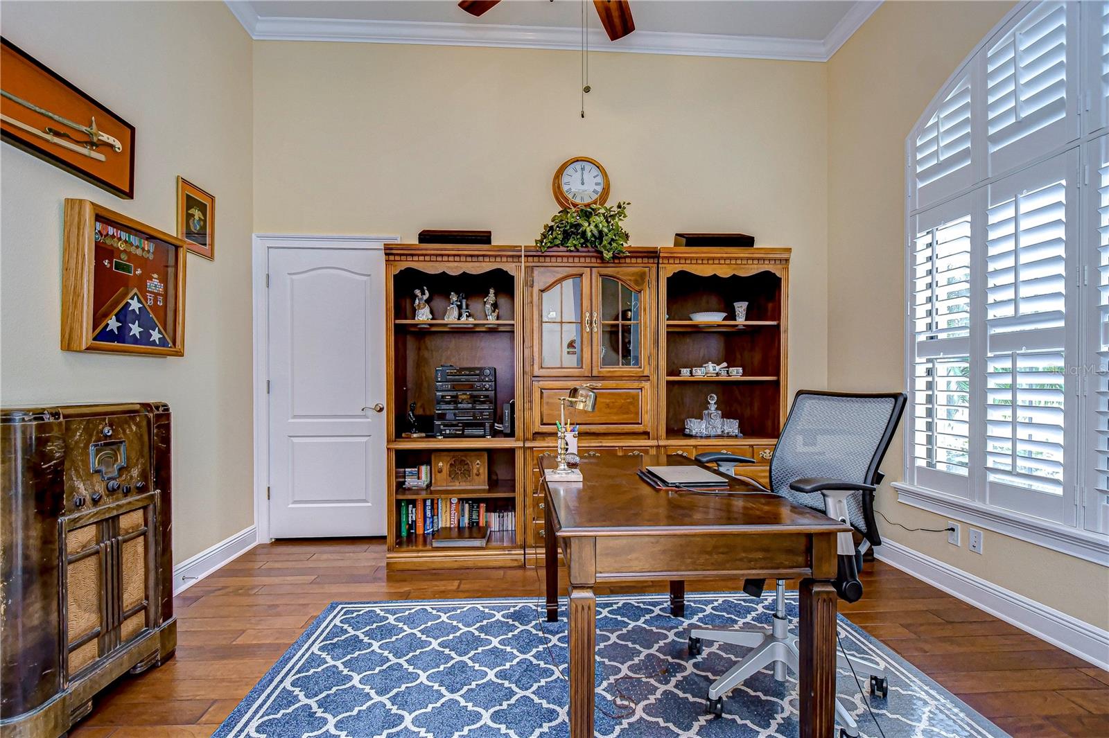 Office space with crown molding and plantation shutters.