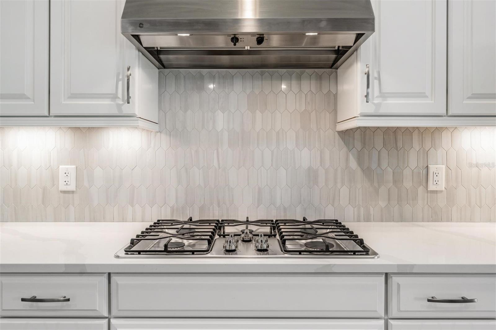 Gorgeous tile backsplash with gas 5 burner cooktop and stainless steel range hood