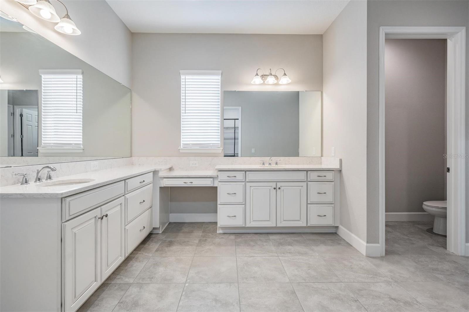 Primary en-suite bathroom with double vanity and separate makeup/vanity space