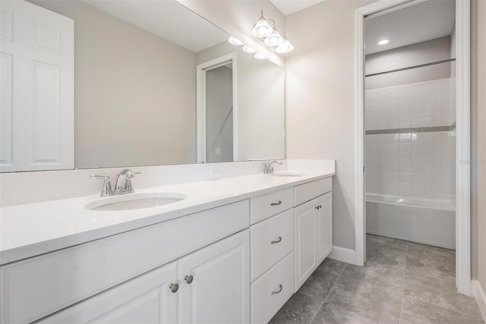 Bathroom #3, shared between bedrooms #3 & #4, double sink vanity, with pocket door access to tub/shower combo and toilet