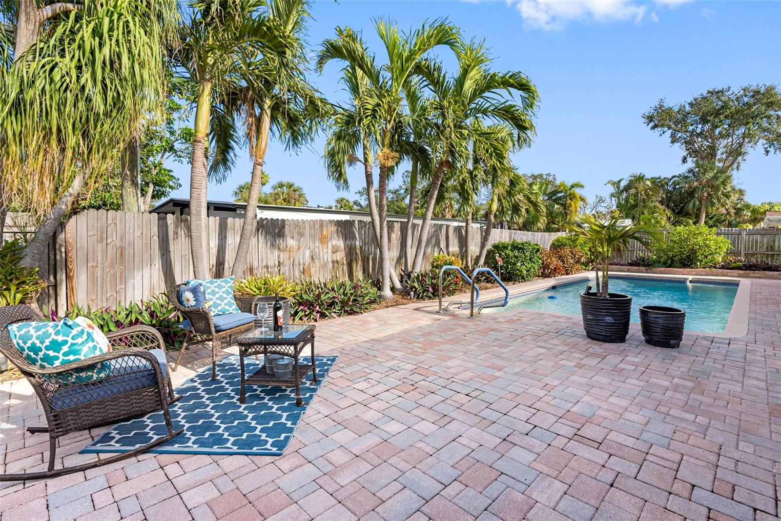 Large pool with a new pump (2024) and paver deck surrounded by lush greenery.