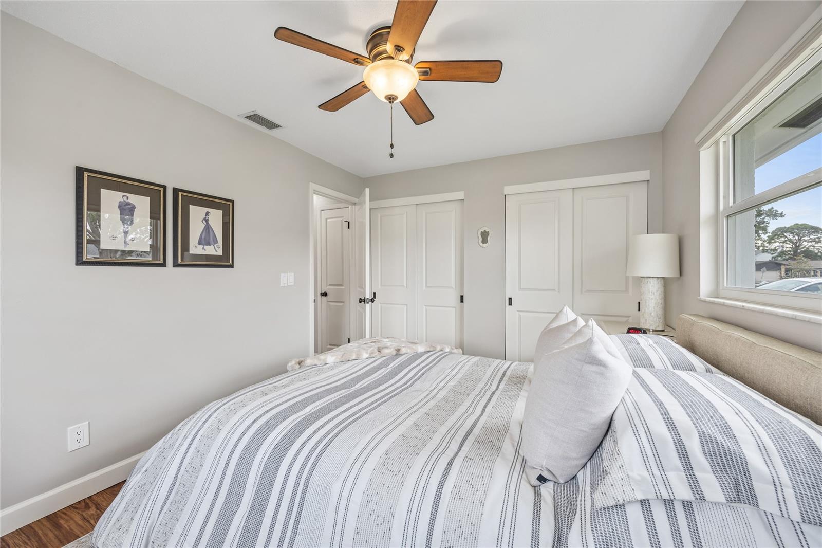 The primary bedroom features two windows, two closets, a ceiling fan, and stylish luxury vinyl plank flooring.