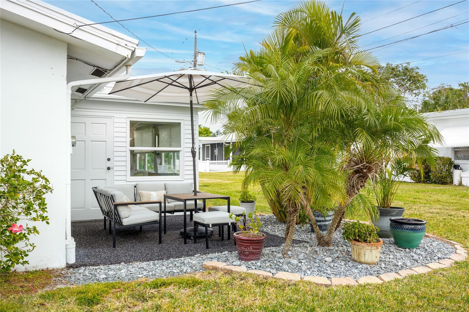 This cozy back patio area has beautiful tropical plants to create privacy.