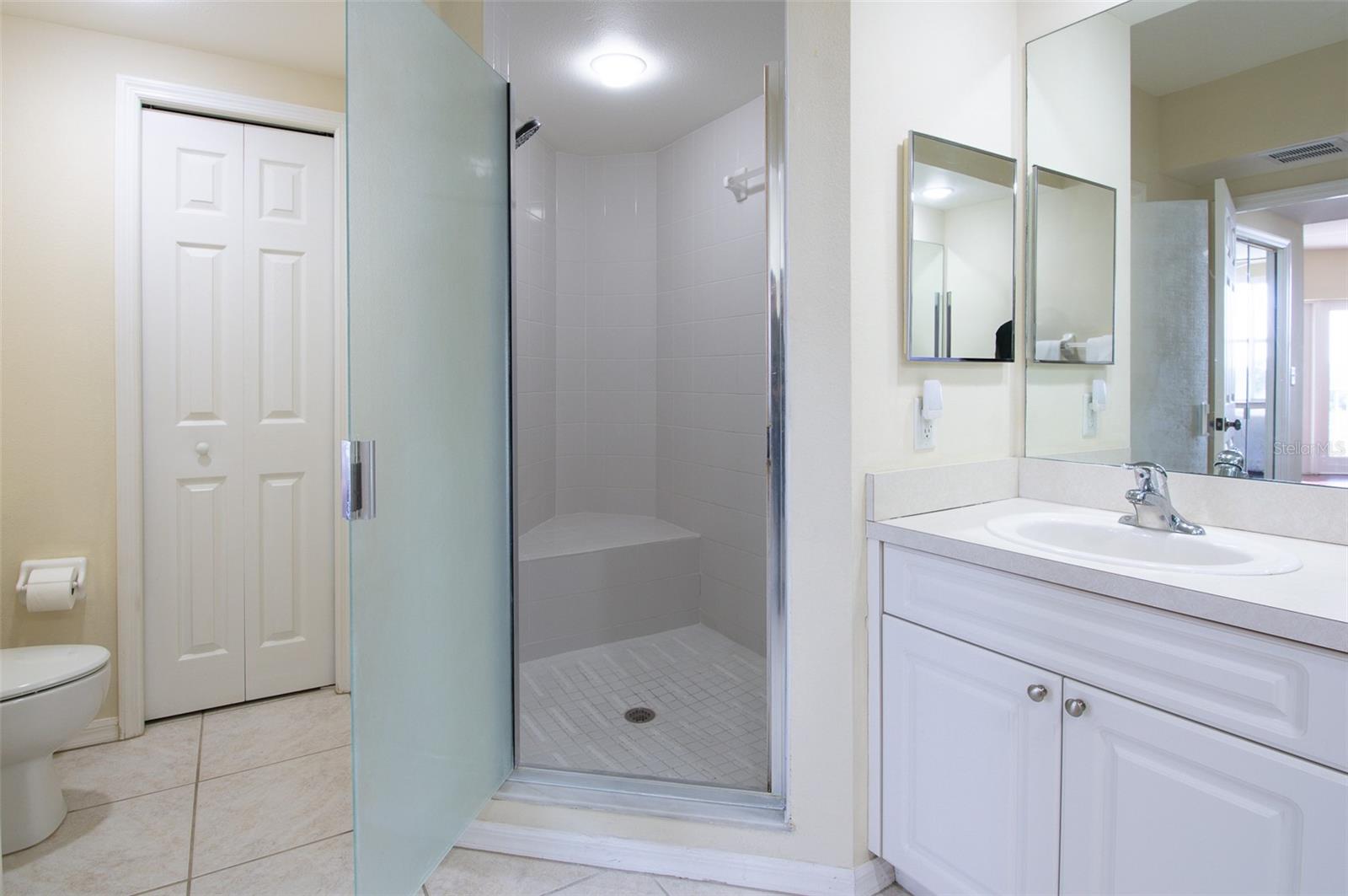 The shower features a seat and a separate area with a linen closet.