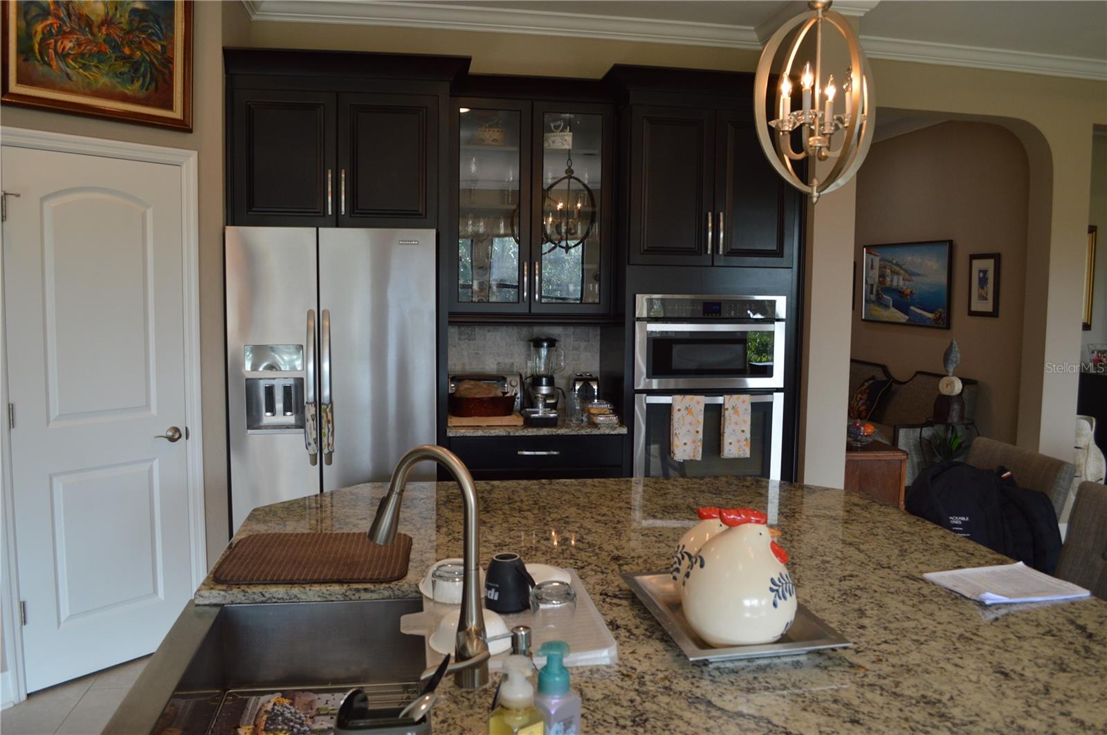 Side view of the kitchen; refrigerator and in-wall oven and microwave.