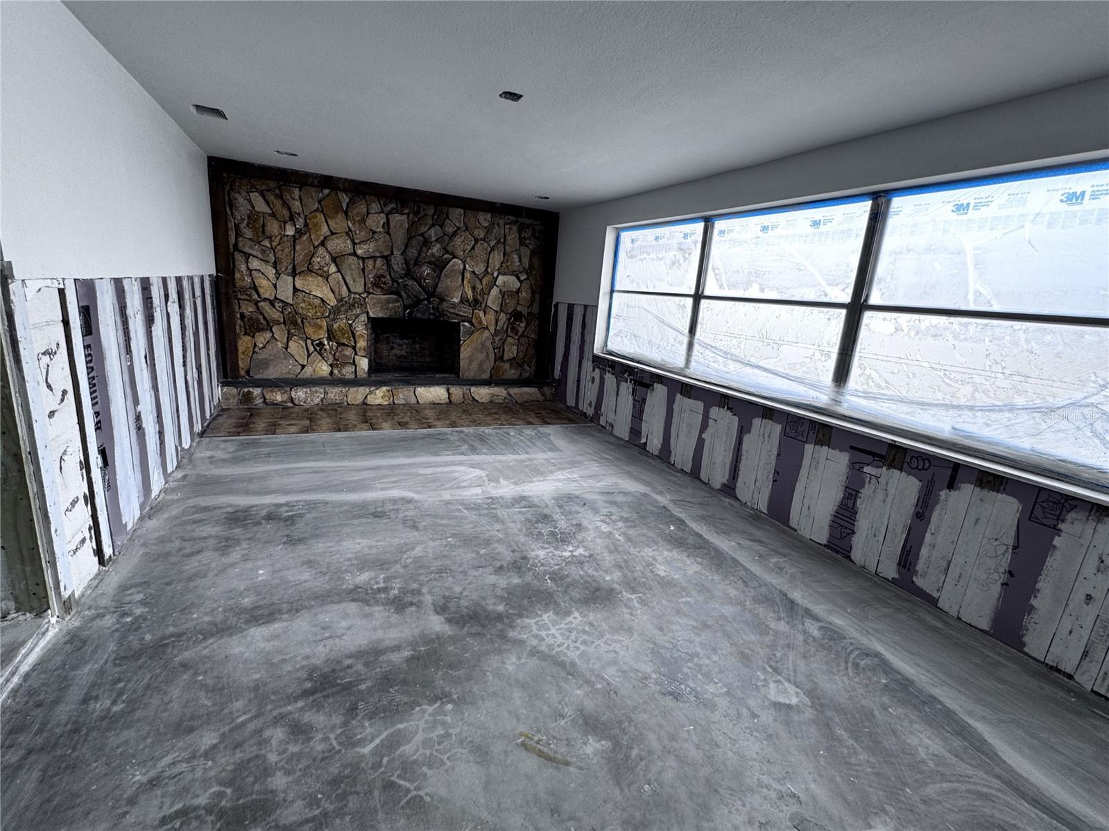 Family Room with stone fireplace and plenty of light with canal view